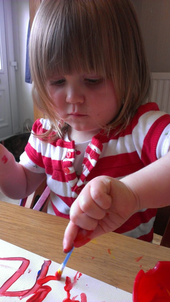 Little girl concentrating on her painting