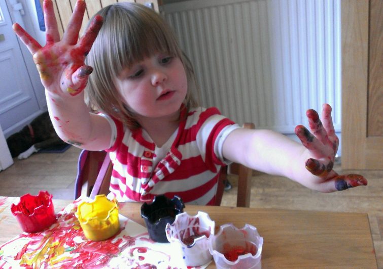 Little girl with paint all over her hands - messy play activitiy