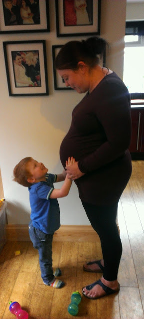 Little boy with his hands on his Mummy's pregnant tummy