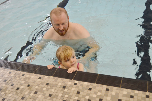 Little girl learning to "monkey walk" on the wall in her Puddle Ducks swimming lesson