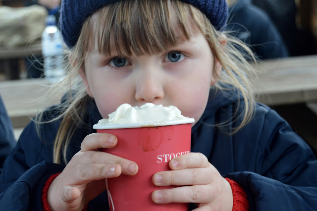 Little girl warming her hands on a hot chocolate with whipped cream at Stockeld Park Christmas Adventure