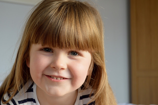 Little girl with golden brown hair and a heavy fringe