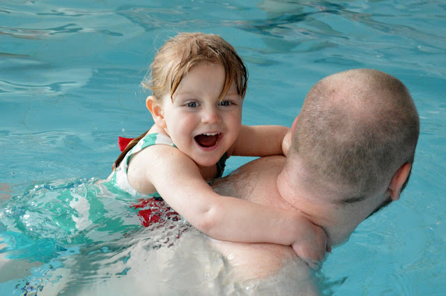 Little girl on Daddy's back in her swimming lesson