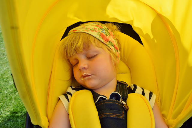 Little girl sleeping in her yellow pushchair at Geronimo Festival