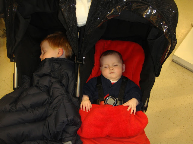 Brother and sister sleeping in twin pushchair