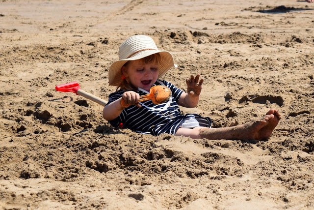 toddler covering herself with sand