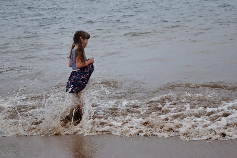 Girl paddling in sea wearing dress