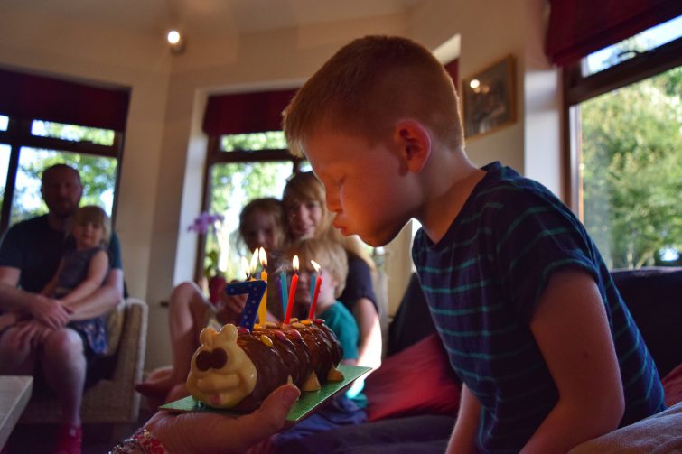boy blowing out candles on birthday cake