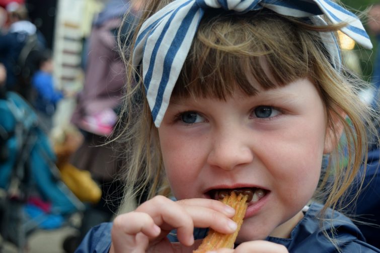 Little girl eating churros at Just So Festival
