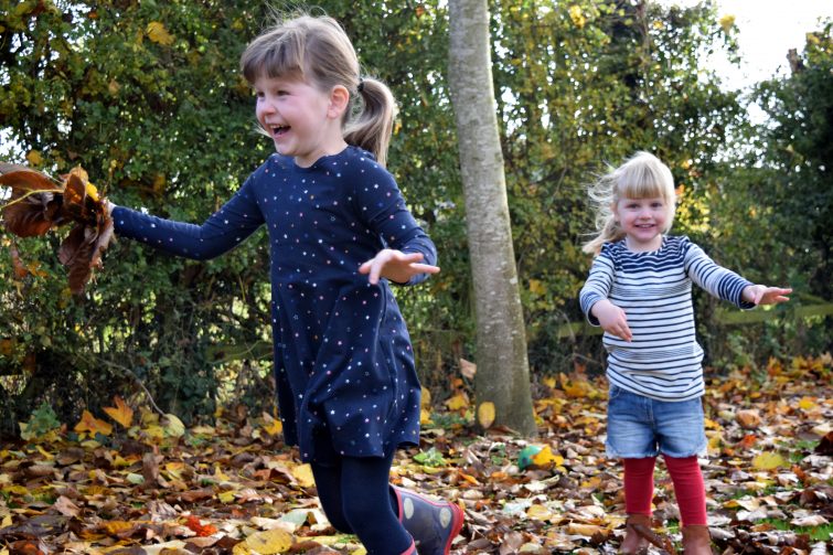 Amy & Chloe throwing autumn leaves in the garden
