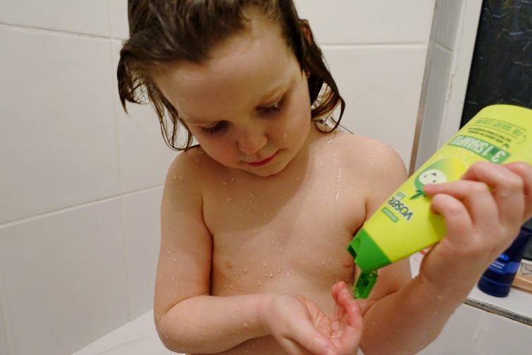 Little girl washing her hair with Vosene Kids head lice prevention shampoo