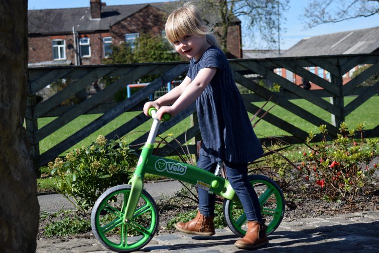 little girl riding green Y Velo Balance Bike