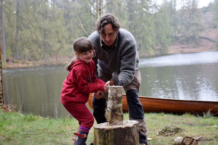 Little girl chopping wood with an axe under supervision from Ben McNutt