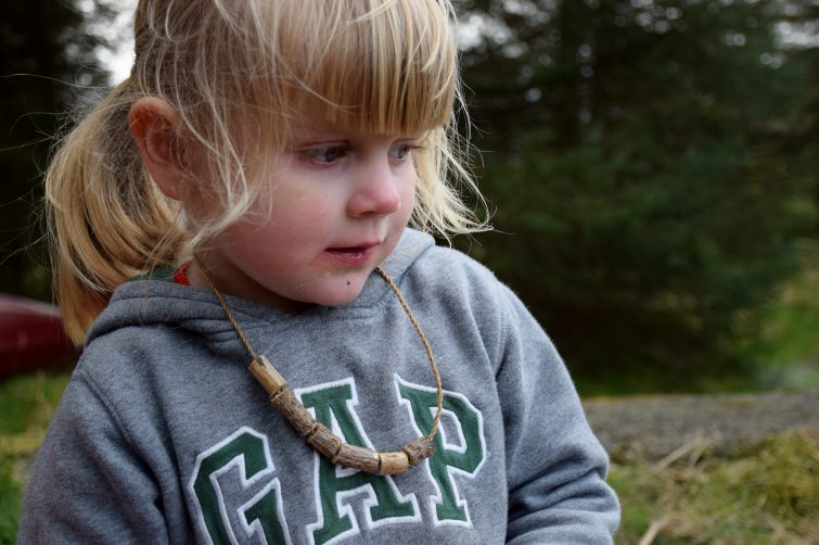 Little girl wearing a necklace made from wooden beads