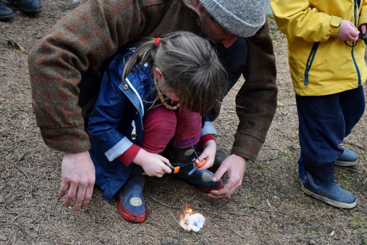 Little girl lighting a fire with flint & steel and a piece of cotton wool