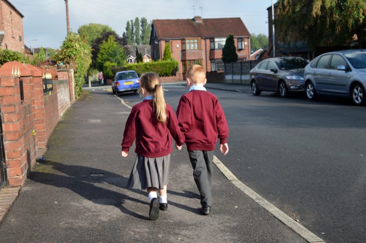 brother and sister walking to school in September - back to school