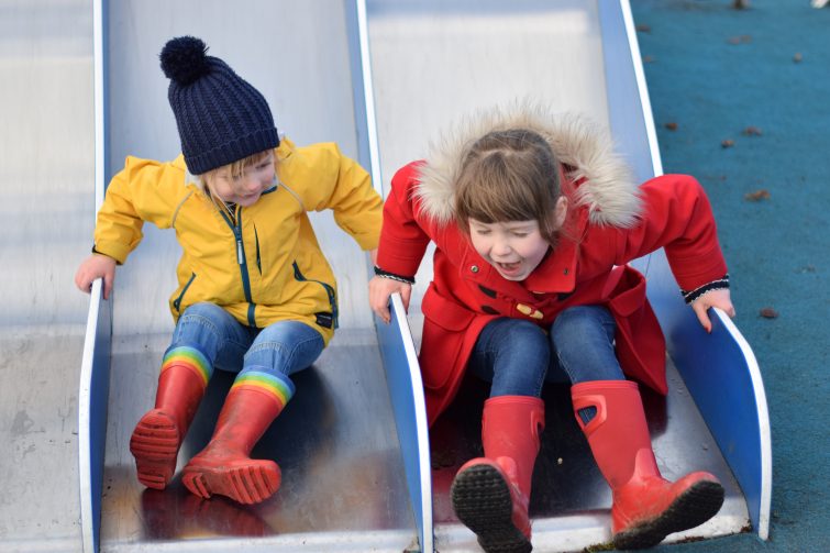 Brightly dressed kids playing on the slide in the park