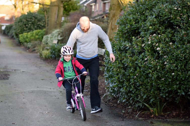 Daddy teaching his little girl how to ride her bike