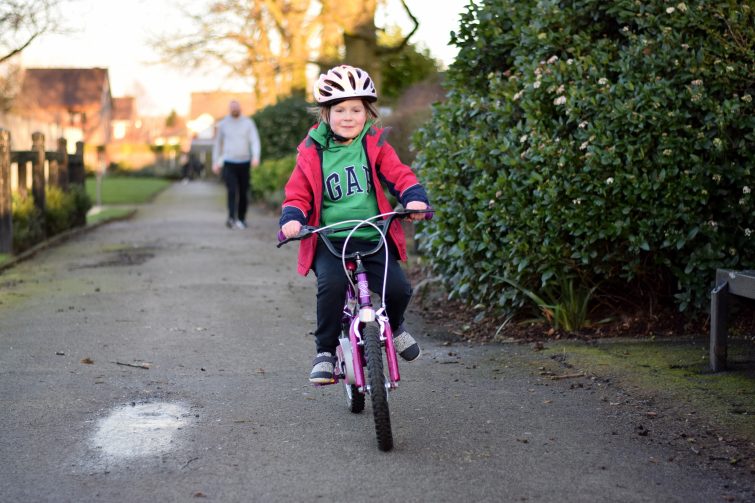 Little girl wearing helmet and riding her bike by herself