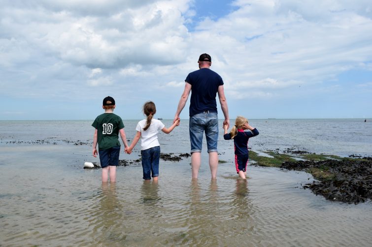 Children standing in the sea with their Daddy