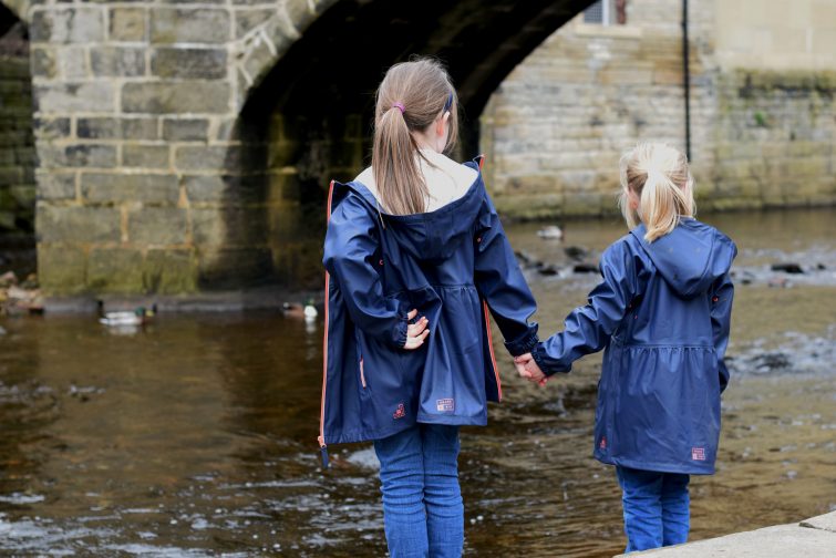 Sisters wearing matching Grass & Air rain macs