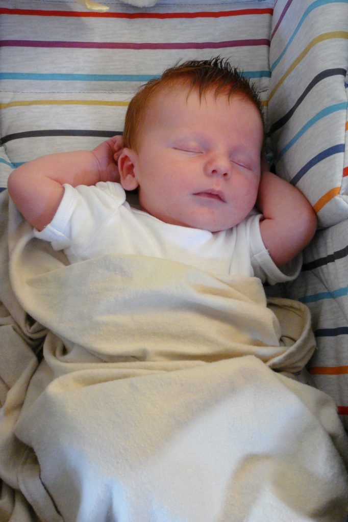 Sleeping baby looking relaxed with his arms behind his head