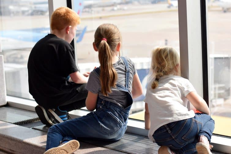 Kids watching planes out of the window at Manchester Airport