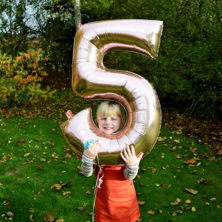 Cheeky little girl with her head in a fifth birthday balloon