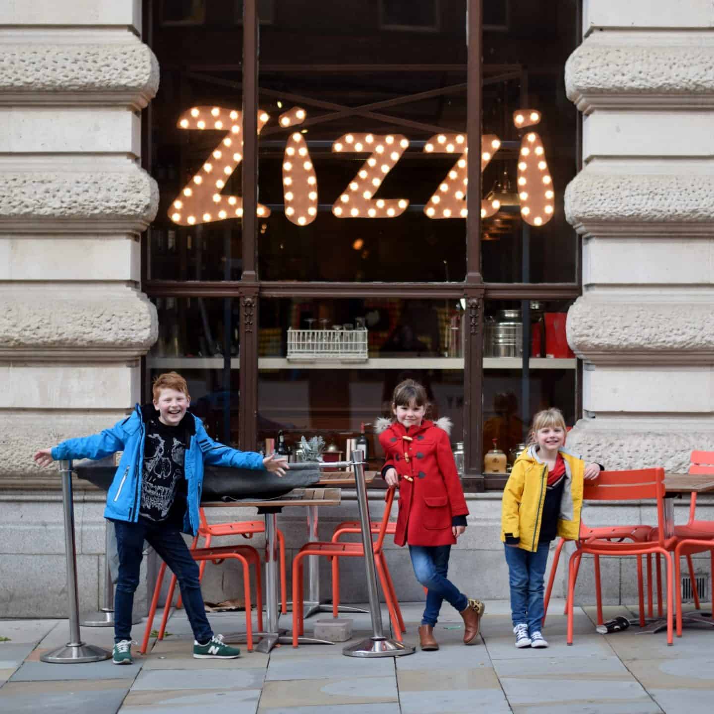 Siblings in bright coats outside Zizi in Manchester