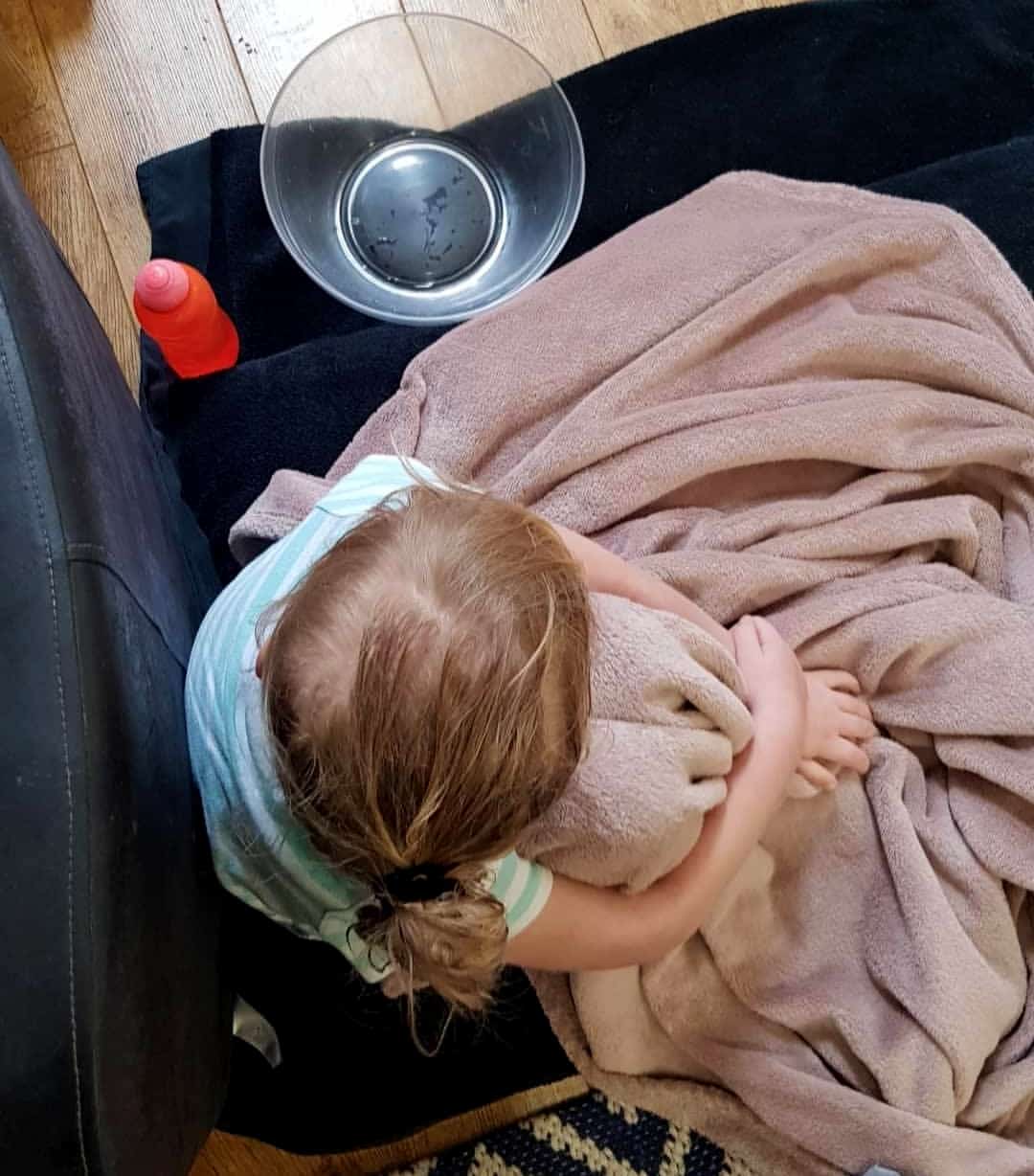Poorly child with sick bowl and blanket