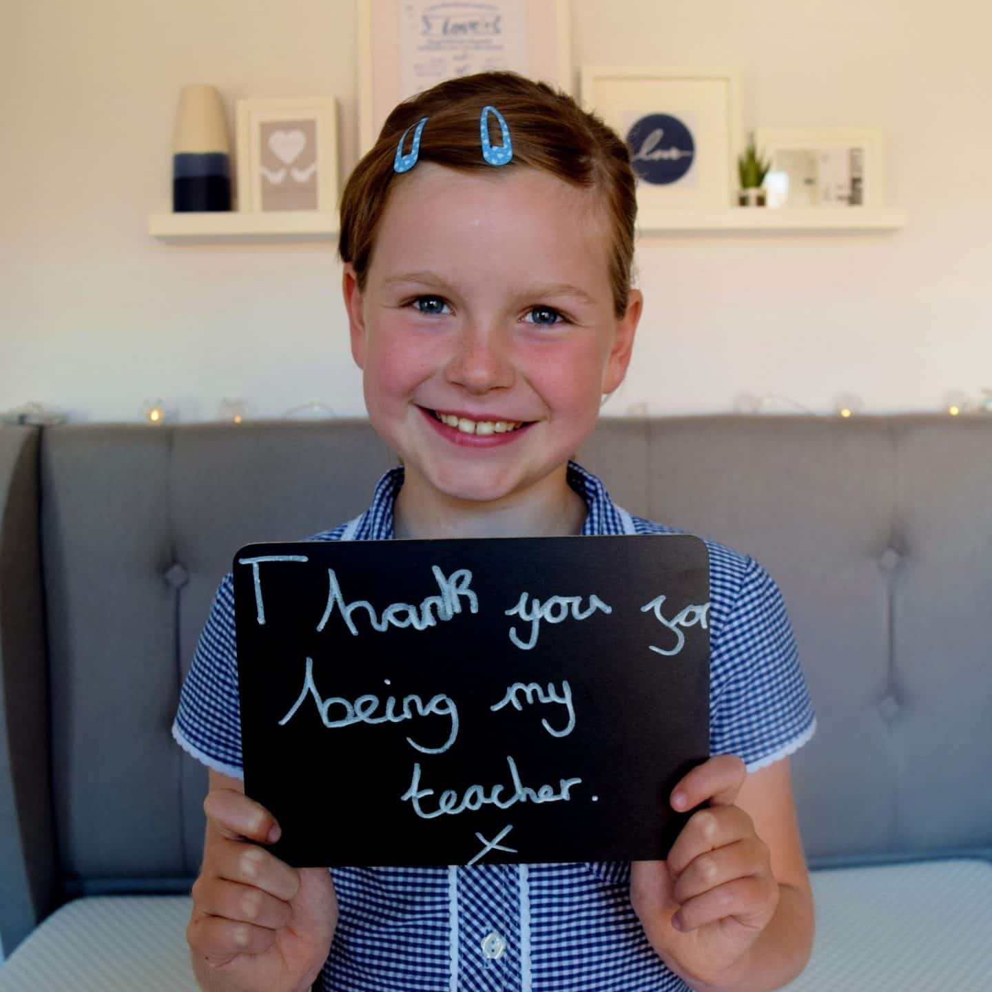 Little girl with chalkboard message which reads "Thank you for being my teacher"