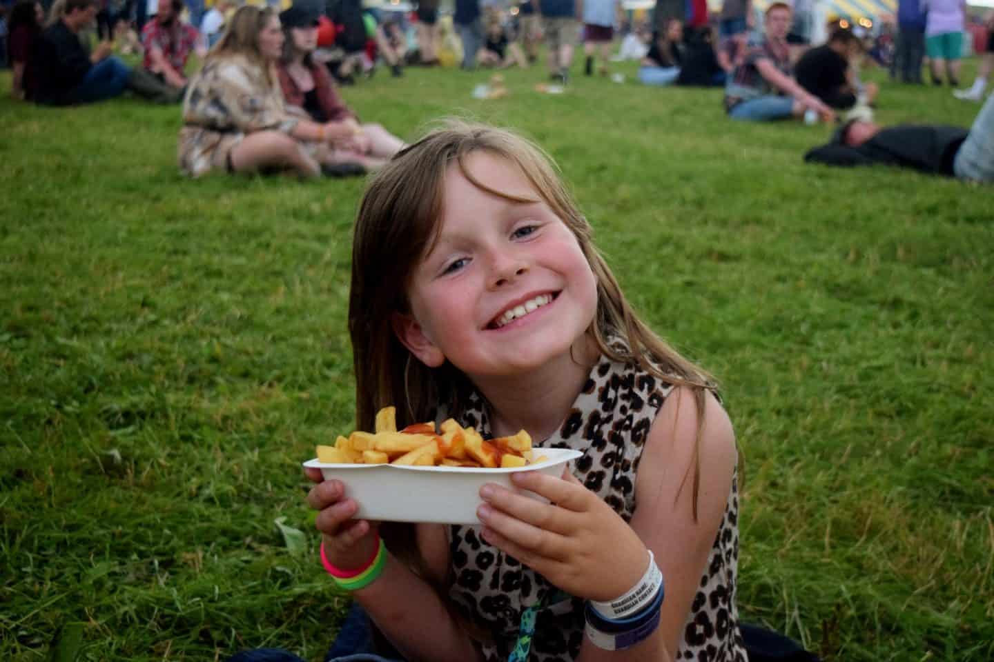 Little girl eating expensive chips at a festival