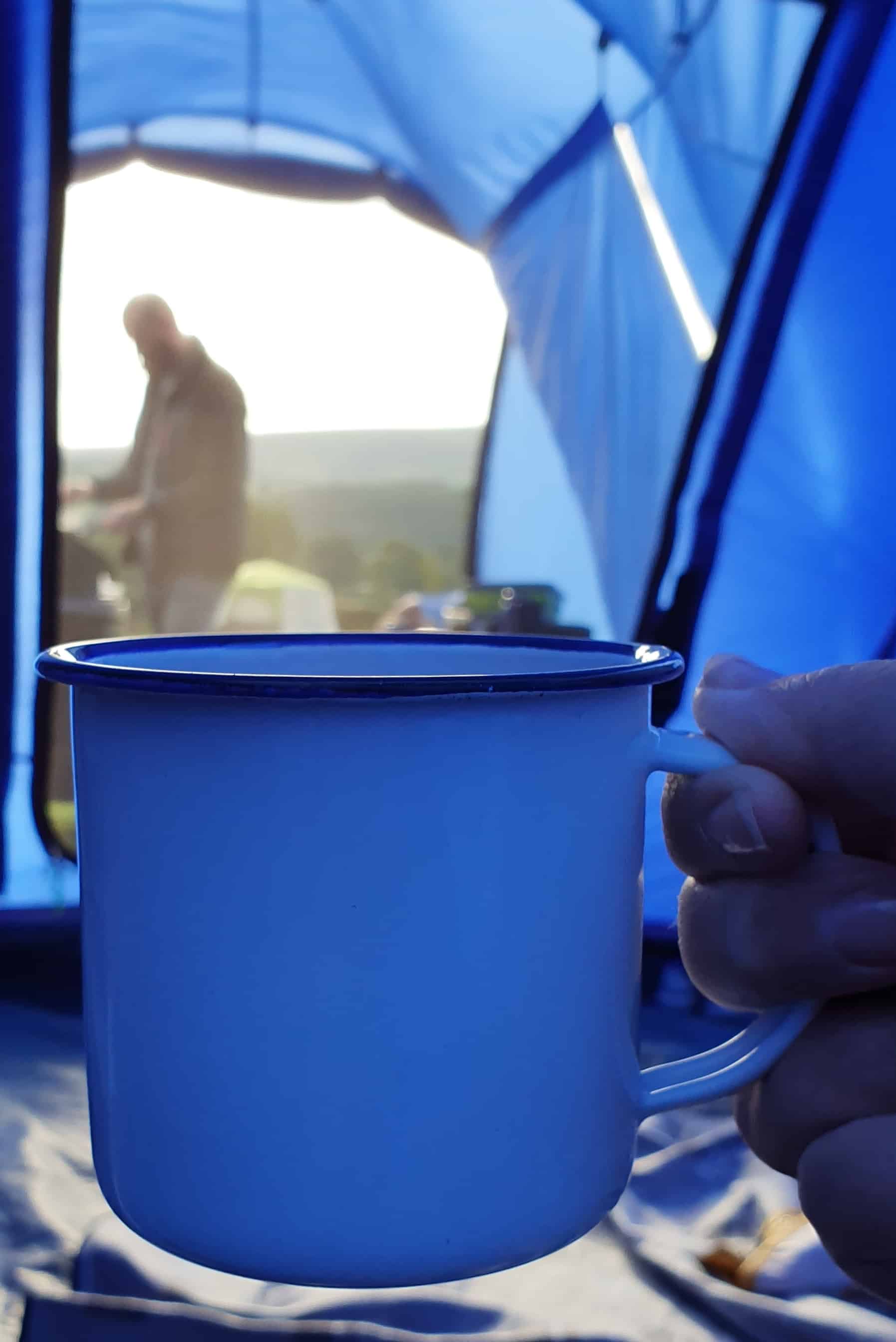 Hot drinks to start the morning when camping - view of camping cup looking out of the tent