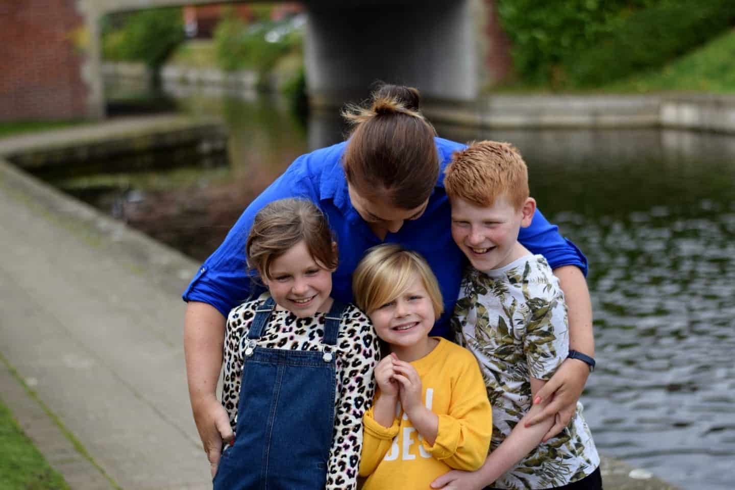 Mum cuddling three children in her arms at once