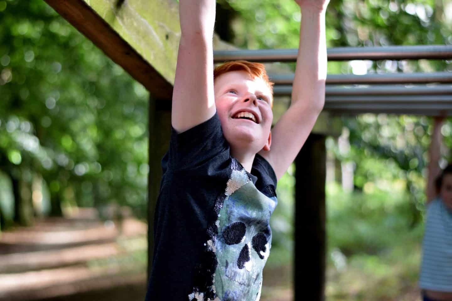boy doing the monkey bars on the Trim Track at Landal Darwin Forest