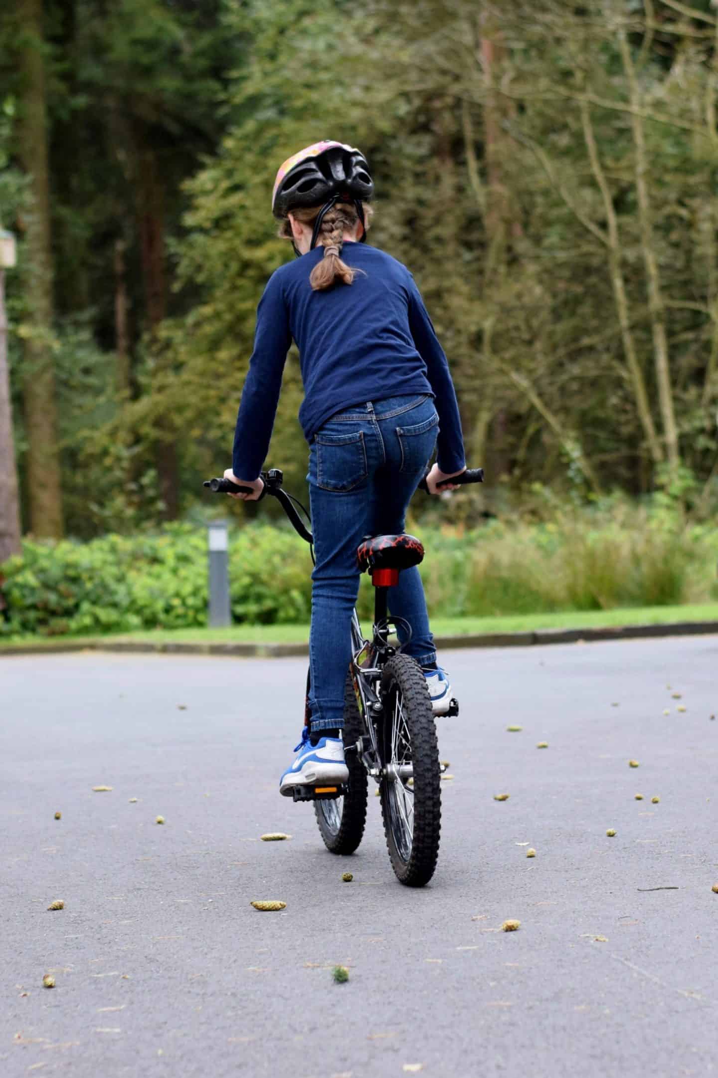 Little girl standing to ride her bike