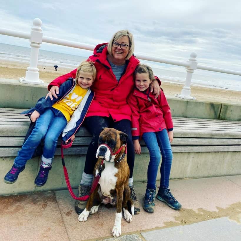 girls and their granny wrapped up warm at the seaside walking a boxer dog
