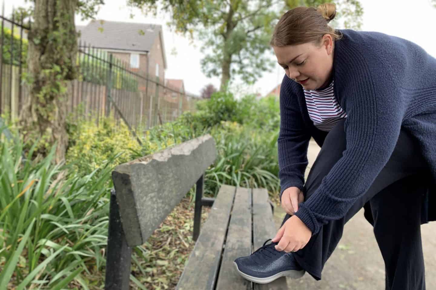 Fastening shoe laces on park bench