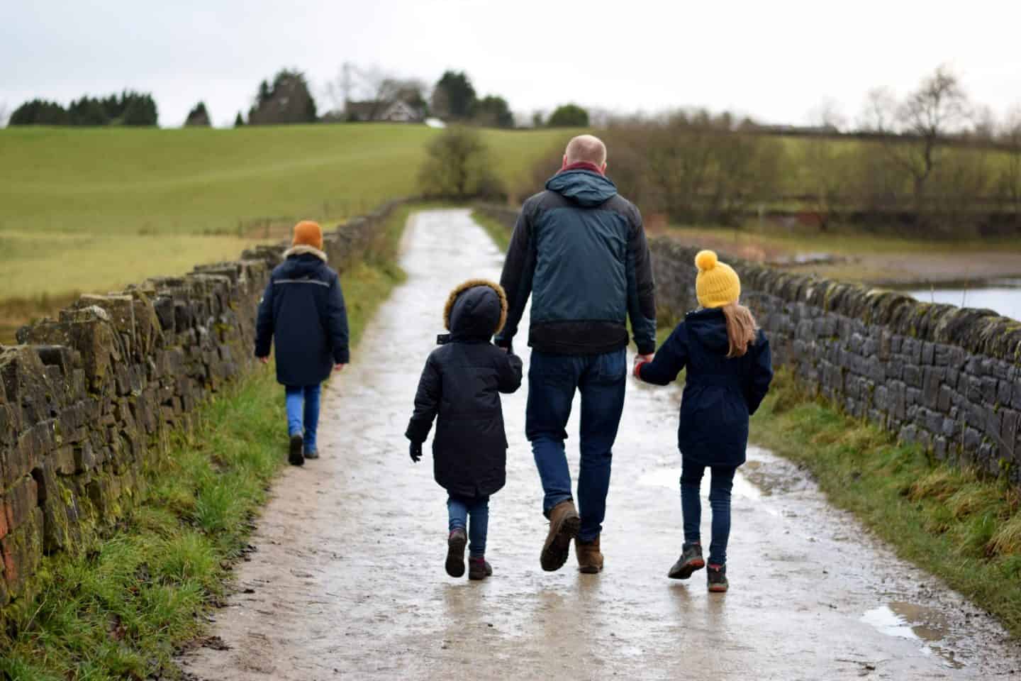 Girls holding hands with their Daddy on a muddy lane