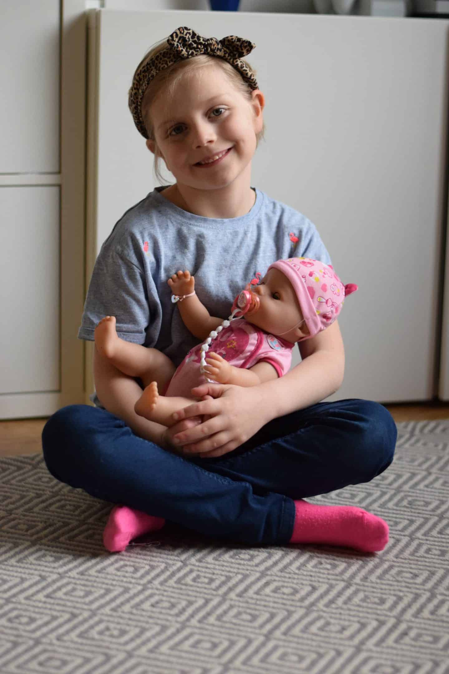 Little girl cuddling her new BABY born soft touch doll