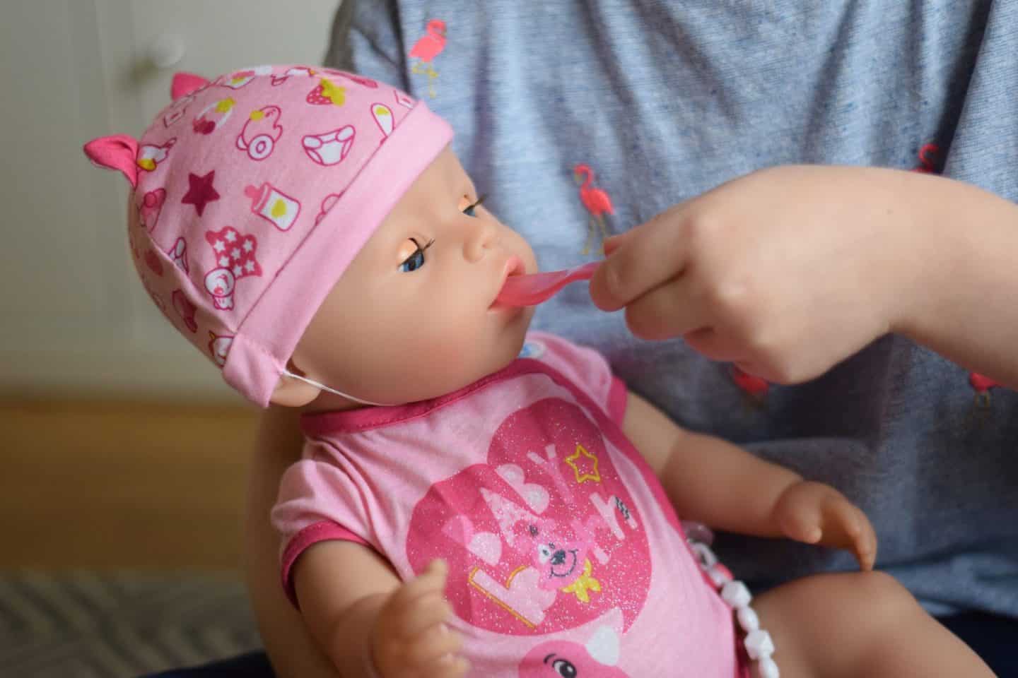Little girl's hand feeding her baby doll with a spoon