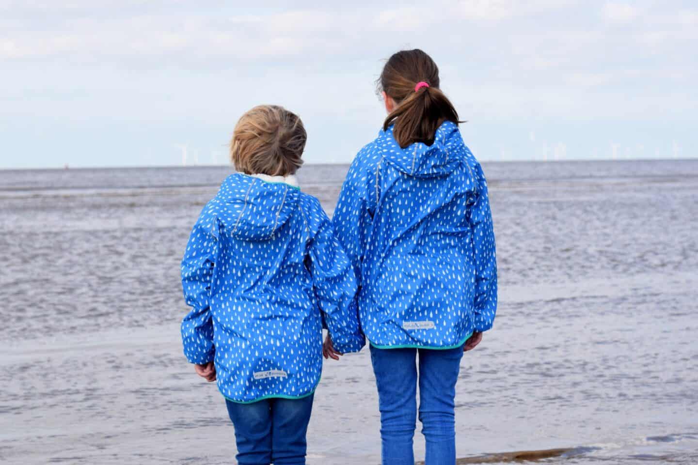 Girls looking out to sea in Muddle Puddles raincoats