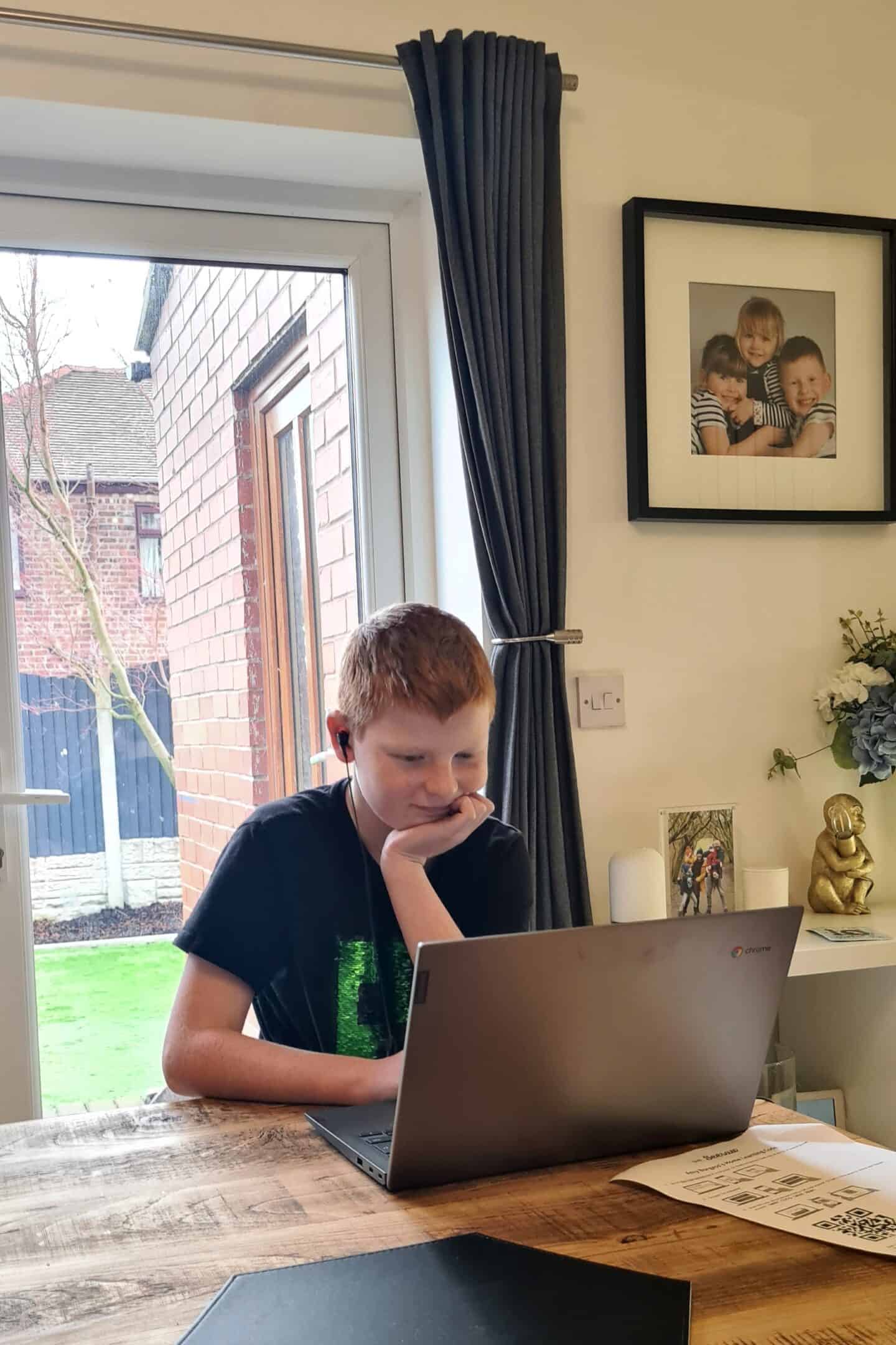 Secondary school child sitting at the dining table to complete his online learning during lockdown