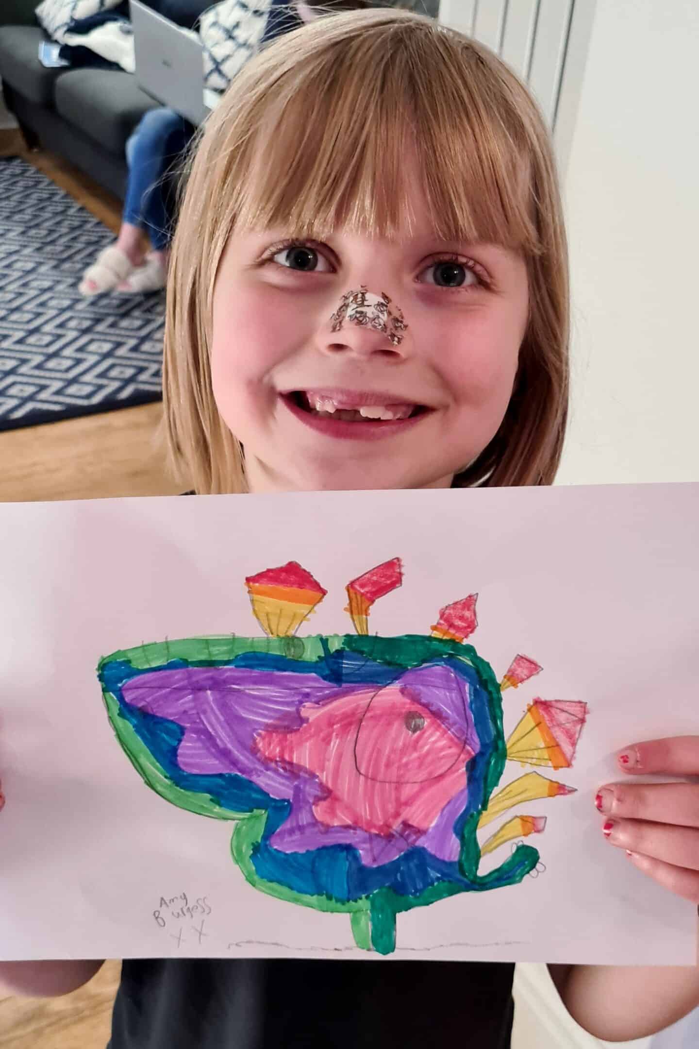 Girl showing her drawing as part of a home learning task