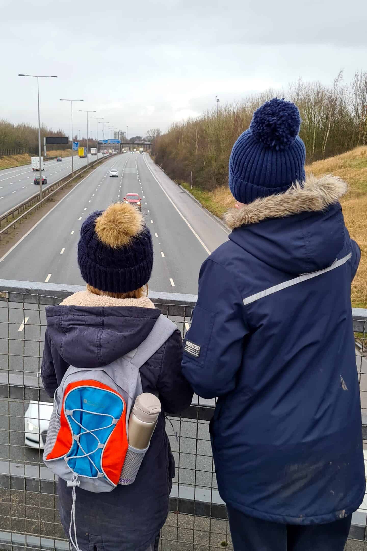 Children on a motorway bridge waving to lorry drivers