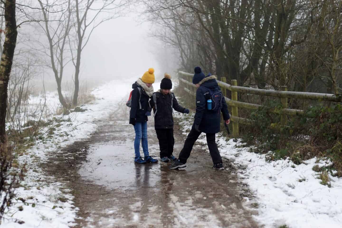 Children breaking icy puddles on a wintery walk