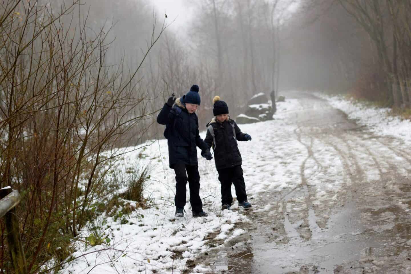 Brother and sister holding hands to navigate muddy puddles