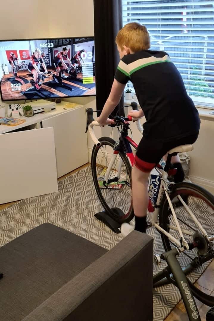 Boy using a turbo trainer with his road bike to do an online spinning class during lockdown