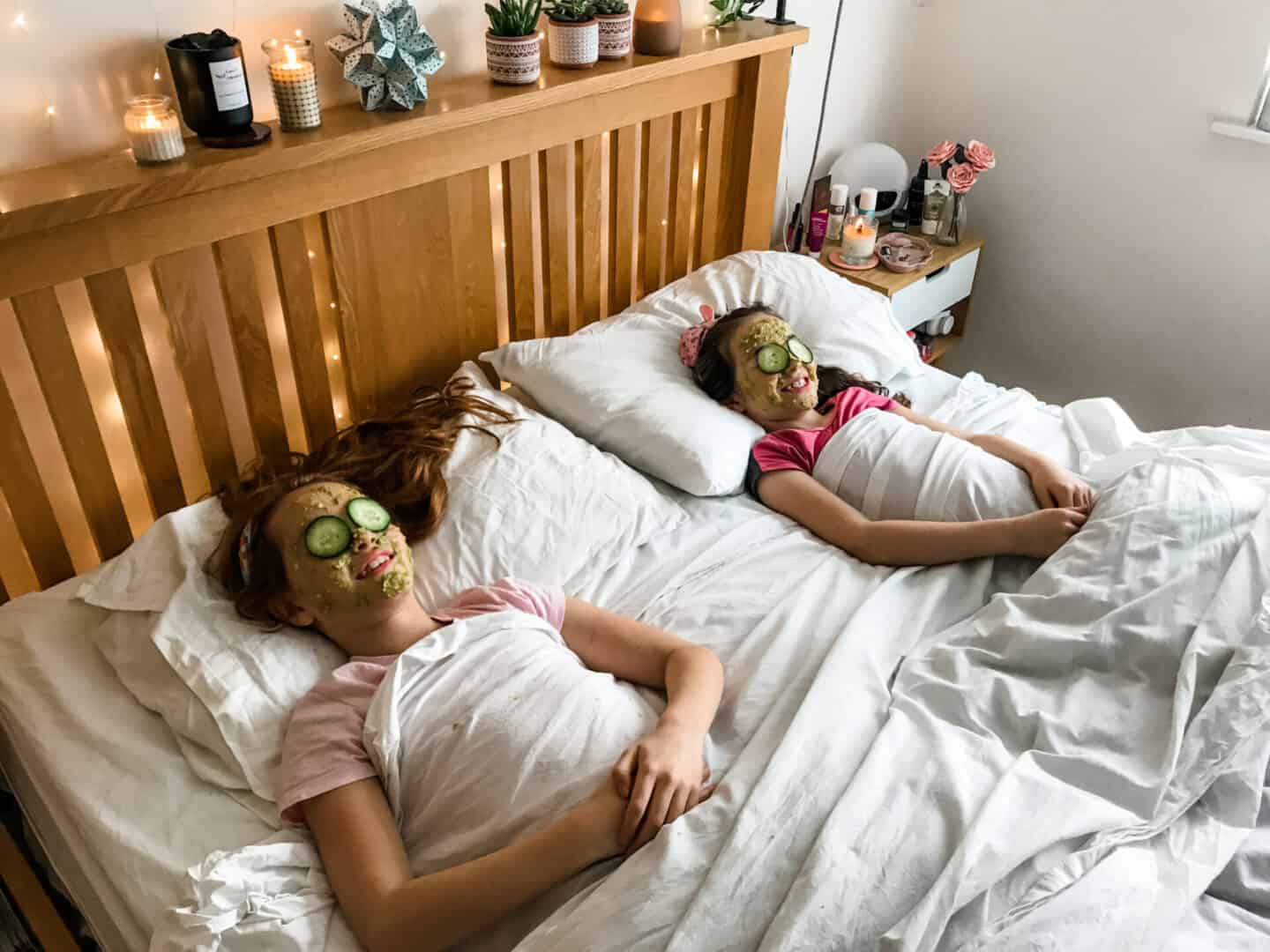 How to set up a relaxing spa day at home with the kids - two girls lying in bed wearing home made face masks and cucumber on their eyes!