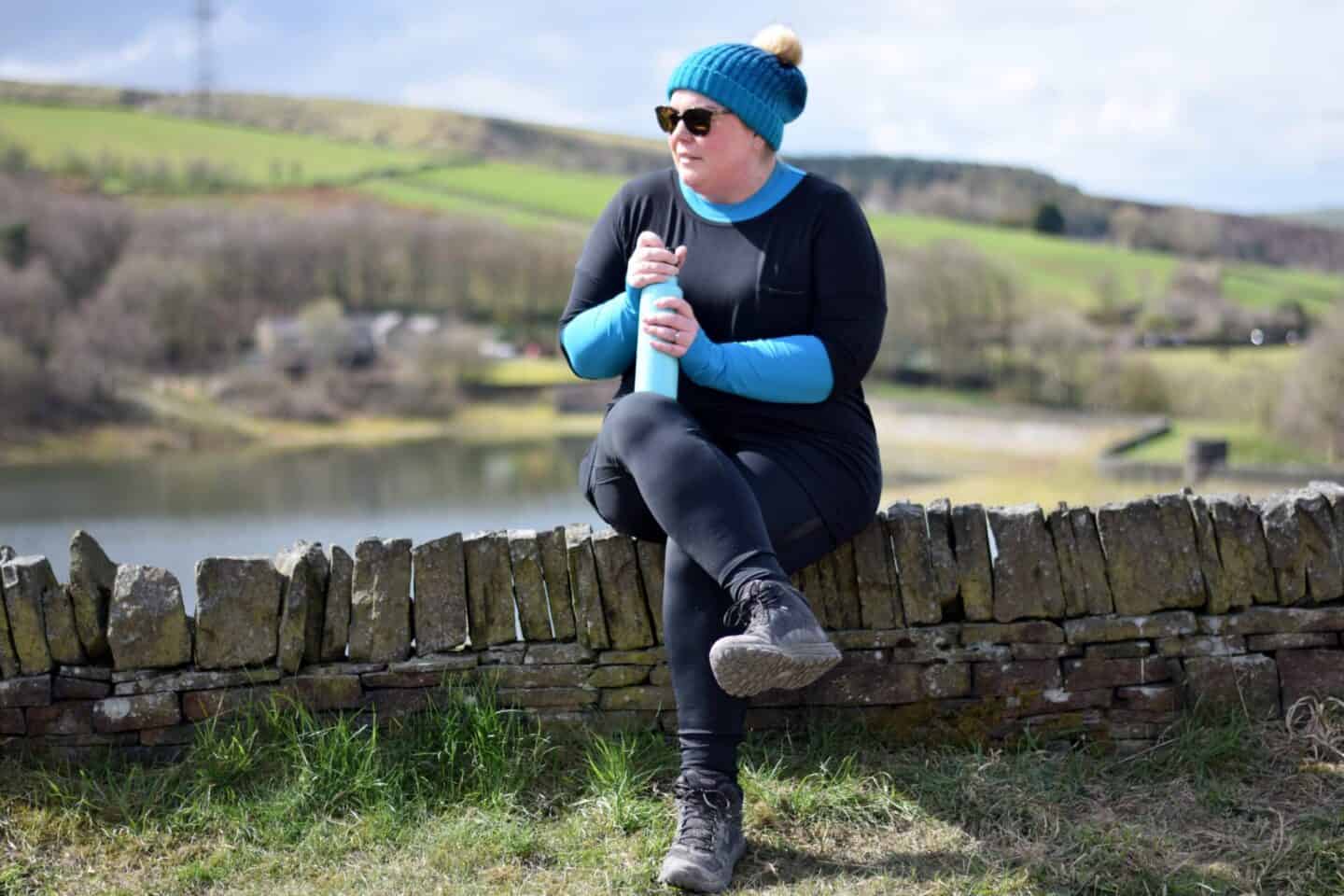 Colette sitting on a wall, stopping for a hot drink on a reservoir walk